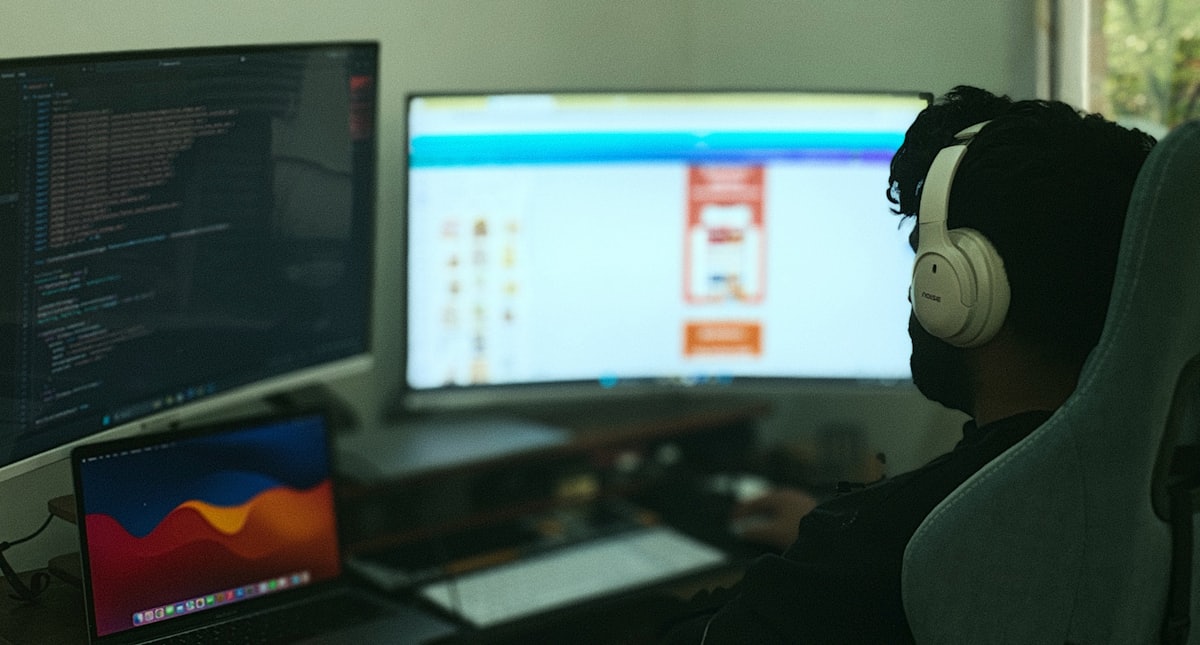 An engineer at a two screen workstation, an editor open on one of them.